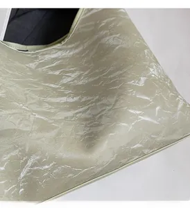 Close-up of light green tote bag with metallic wrinkled texture and soft leather finish