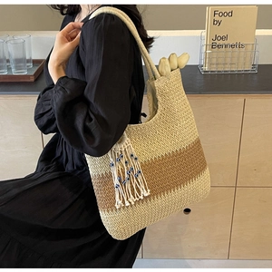 Detail of woven tote bag featuring evil eye charm and fringe tassel in a lifestyle setting