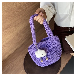 Detail of purple hand-woven crochet tote bag with a white plush cloud charm accessory