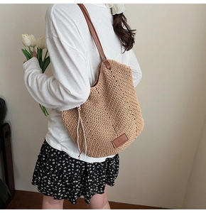 Detail of woven straw tote bag with brown leather straps and square logo patch