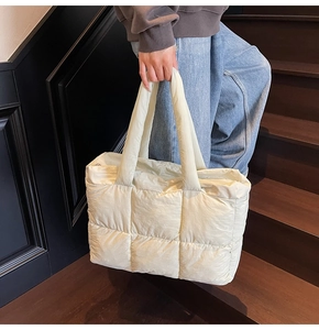 Detailed view of cream quilted tote bag with spacious interior and soft padded handles