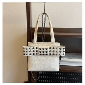 Détail d'un sac à main blanc en cuir grainé avec grand nœud à rivets sur support bois