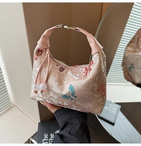 Close-up of pink embroidered dumpling bag with butterfly floral patterns and bead charms