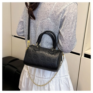 Detail der schwarzen Boston-Tasche mit Prägemuster und Goldkette am Modell