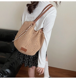 Detail of woven straw tote bag with brown leather straps and side cord knot detail