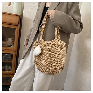 Close-up of hand-woven hollow tote bag with a soft white plush cloud charm accessory