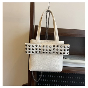 Détail du sac seau blanc crème avec grand nœud à rivets et bandoulière chaîne