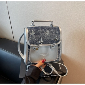 Detail of silver mirror PU leather and blue glitter denim mini backpack with butterfly accents
