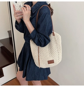 Detail of cream woven tote bag featuring V-shaped texture and brown leather strap