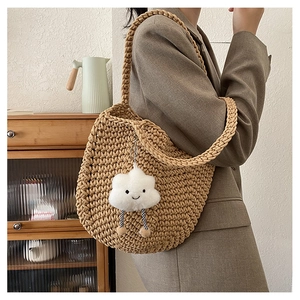 Detail of hand-woven hollow knit tote bag featuring a cute white cloud plush pendant