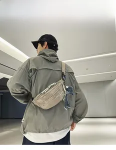 Male model wearing khaki nylon crossbody chest bag with adjustable strap and plush charm
