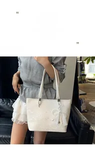 Detail of white lace tote bag featuring elegant bow with pearl and heart charms