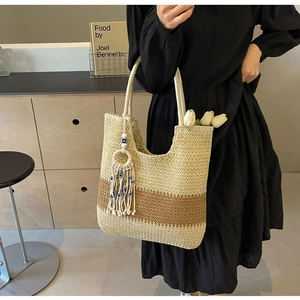 Close-up of woven straw tote bag featuring color-block design and bohemian tassel detail