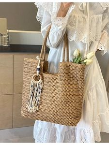 Handwoven straw tote bag with evil eye tassel charm and spacious interior for beach trips