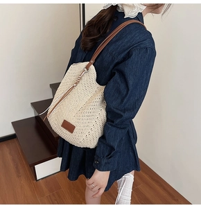 Detail of woven cotton tote bag featuring brown leather shoulder straps and logo patch
