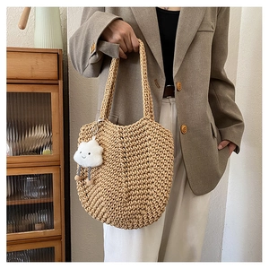Detail view of beige hand-woven tote bag with textured knit pattern and cloud charm