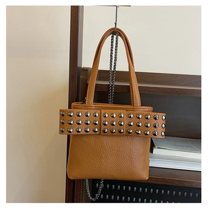 Gros plan du sac seau en cuir caramel avec clous métalliques et détail de nœud