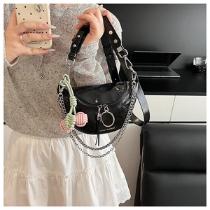 Detail view of black crescent bag with chunky metal chain and tassel zipper pull