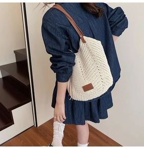 Detail of hand-woven beige tote bag with brown leather shoulder strap and decorative tag