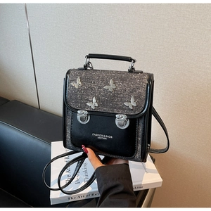 Detail of black backpack with grey shimmer flap and silver butterfly metal ornaments