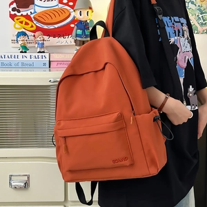 Dettaglio dello zaino in nylon arancione con logo CDMNQ e tasca frontale con zip