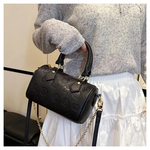 Détail du sac Boston noir avec motifs de dessins animés et bandoulière en chaîne dorée