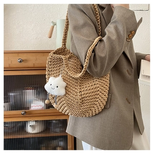 Detail of beige hand-woven crochet tote bag with a cute cloud pendant on a shoulder strap
