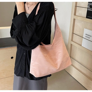 Detail of a pink tote bag showing the pleated texture and long shoulder strap on a model
