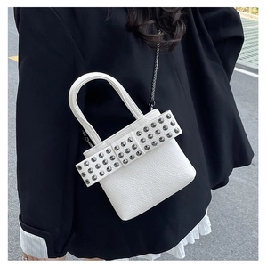 Détail du sac blanc en cuir litchi avec nœud à rivets et bandoulière en chaîne