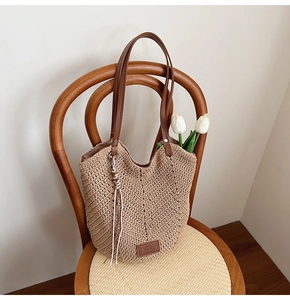 Close-up of handwoven khaki tote bag with brown leather label and stylish tassel detail