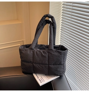 Close-up of black quilted puffer tote bag with waterproof nylon texture on a sofa