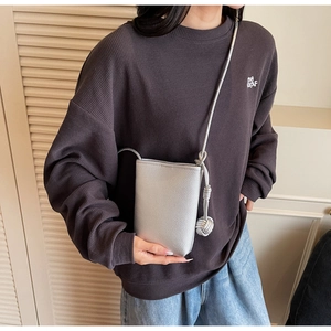 Close-up of a silver crossbody phone bag with litchi grain texture and knot detail