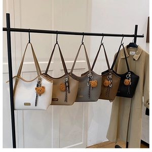 Detail view of five multi-colored large tote bags hanging on a rack with bear charms