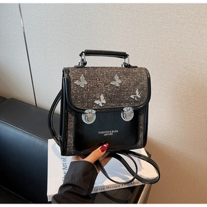 Detail of black faux leather backpack with diamond coating and metal butterflies