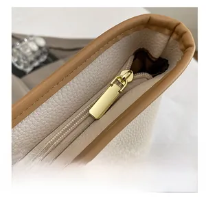 Dettaglio della cerniera in metallo e bordo in pelle marrone su borsa beige