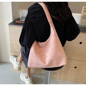 Detailed view of large pink tote bag with glossy wrinkled texture on shoulder strap