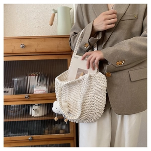 Detail of hand-woven cream tote bag with a white plush cloud charm and sturdy texture