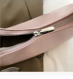 Detail eines glatten silbernen Metallreißverschlusses an einer hellrosa Leder-Halbmondtasche