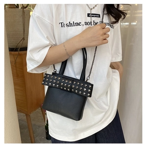 Détail du sac en cuir grainé noir avec nœud à rivets métalliques et bandoulière chaîne