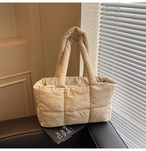 Detail of beige quilted tote bag with padded handles and large capacity design