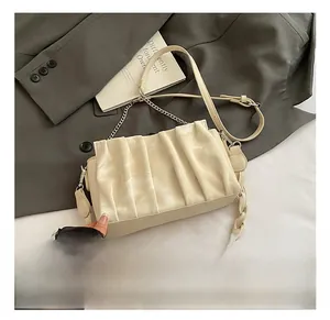 Detail showing creamy white pleated cloud bag with metal chain and woven shoulder strap