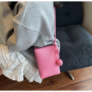 Close-up of bright pink textured leather phone bag with stylish large knot shoulder strap