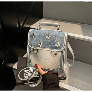 Detail of silver metallic backpack with denim flap and silver butterfly metal buckles
