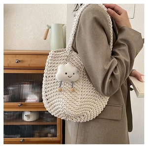 Detail of cream woven tote bag featuring a cute cloud plush charm and textured knit pattern