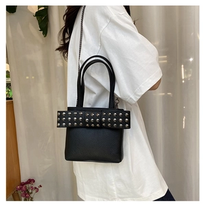 Détail du sac à main en cuir noir avec nœud clouté argenté et bandoulière chaîne
