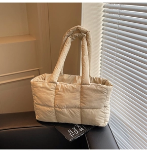Detail shot of beige quilted puffer tote bag with large square stitching and padded handles