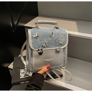 Detail of denim and silver leather backpack featuring metallic butterfly ornaments