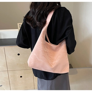 Detail of pink tote bag with unique wrinkled texture shown on shoulder with black top