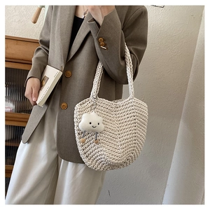 Detailed close-up of woven cream tote bag texture with cute cloud pendant accessory
