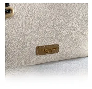 Macro shot of lychee grain leather texture with a brown fashion brand tag on a tote bag